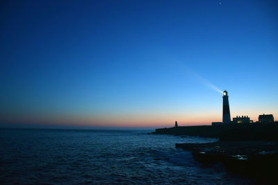 Lighthouse by sea against romantic sky