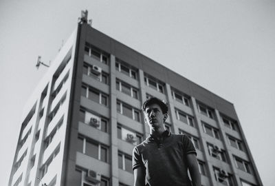 Low angle view of man standing against building against clear sky