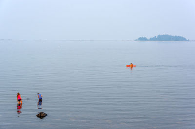 People on sea against clear sky