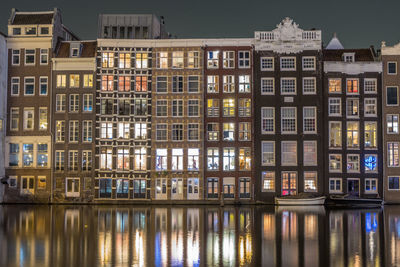 Reflection of buildings on damrak canal at night