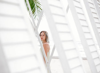 Portrait of woman looking through lounge chairs