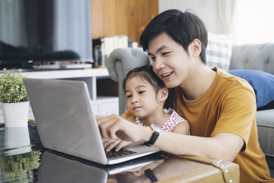 Women looking at camera while sitting in laptop