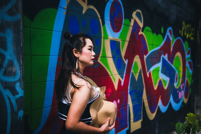 Woman standing against graffiti wall