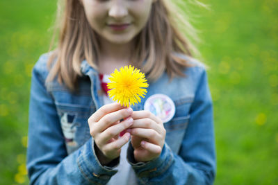 Midsection of woman holding dandelion flower