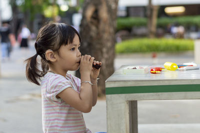 Close-up of cute girl playing with childs play clay at table outdoors