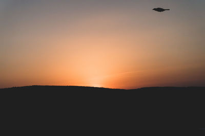 Scenic view of silhouette landscape against orange sky