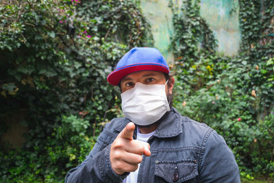 Portrait of man wearing sunglasses standing against plants