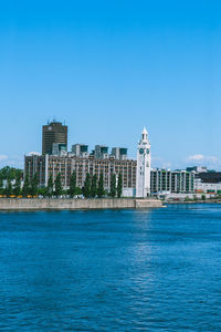 Buildings at waterfront against blue sky