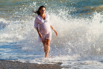 Pregnant woman is jumping on beach. cheerful pregnant woman runs on seashore.