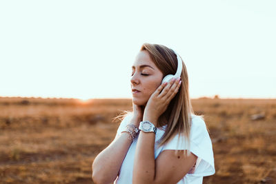 Beautiful woman standing on field against clear sky