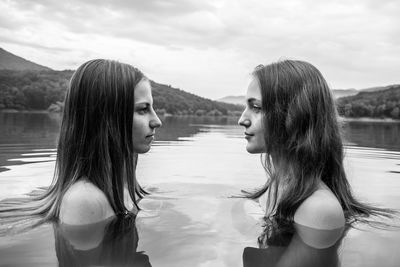 Profile view of shirtless female friends face to face in lake