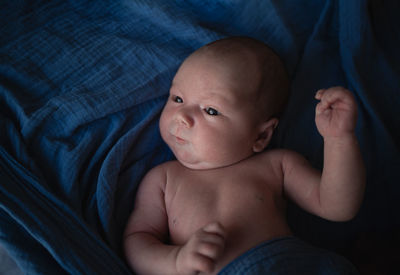 Portrait of shirtless baby boy lying on bed at home