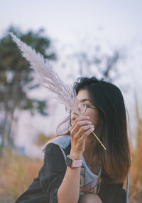 Young woman holding plant looking away