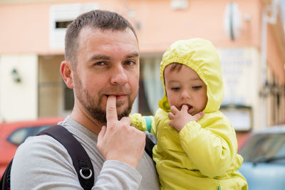 Portrait of father and daughter putting fingers in mouths