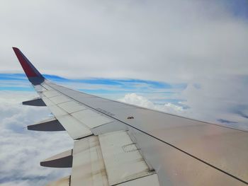 Airplane flying over clouds against sky