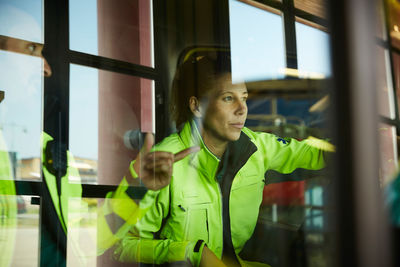 Female paramedic listening to coworker seen through ambulance windshield