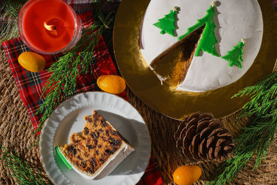 Traditional christmas cake, on background of christmas decorations, top view of slice  on plate.