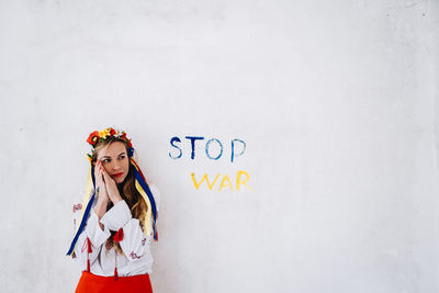 Portrait of young woman standing against white background