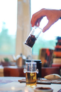 Close-up of hand pouring wine in glass on table