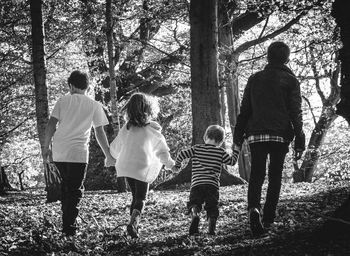 Rear view of children walking in forest