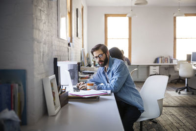 Businessman using laptop while sitting in creative office