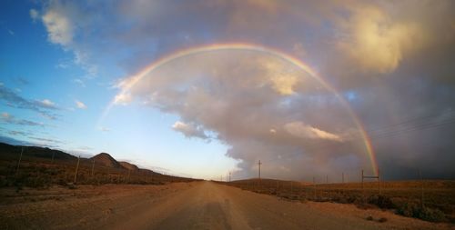 Rainbow over road against sky during sunset