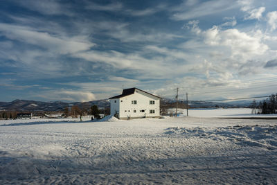 Snow covered houses by building against sky