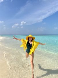 Young woman standing at beach against sky