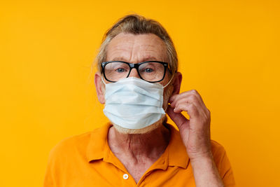 Portrait of woman wearing mask against yellow background