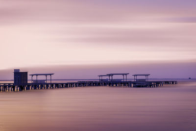 Pier over sea against sky during sunset