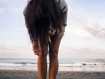 Woman standing at beach against sky