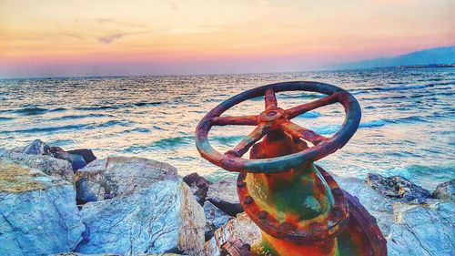 Rusty metal on beach against sky during sunset