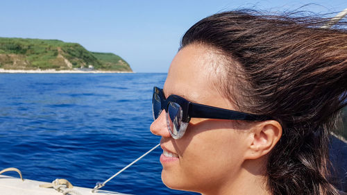 Smiling woman in sunglasses against sea
