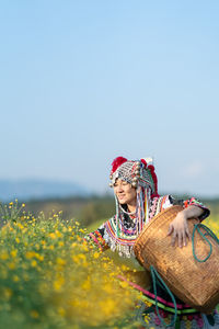 Woman standing by flowering plants against sky