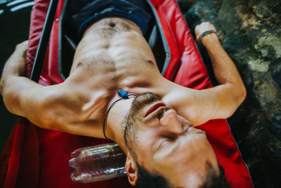 High angle view of shirtless man sleeping on kayak