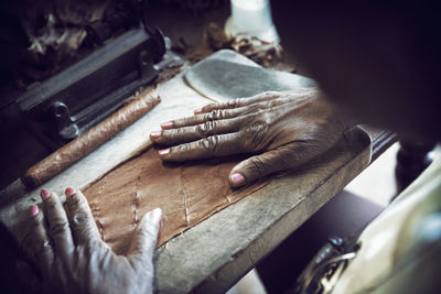 Cropped image of woman spreading leaf while making cigar in factory