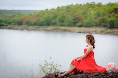 Side view of woman sitting by plants