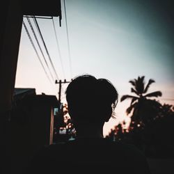 Rear view of silhouette man sitting against sky