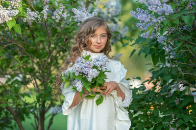 Portrait of girl standing by flowering plants