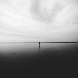 Silhouette man standing in sea against sky