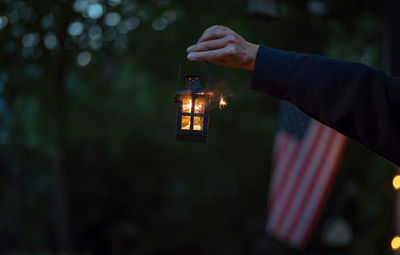 Cropped hand holding illuminated lantern