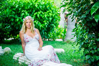 Portrait of young woman sitting against plants