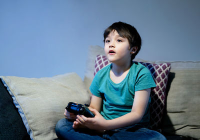 Boy looking away while sitting on sofa