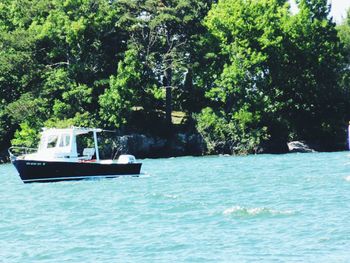 Boats in sea with trees in background