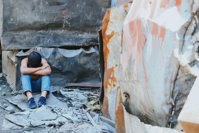 Sad boy sitting by abandoned metal