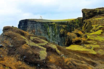 Scenic view of cliffs against cloudy sky