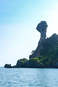 Rock formation in sea against clear sky