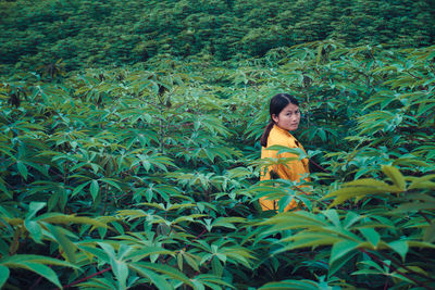 Side view portrait of woman standing amidst leaves on field
