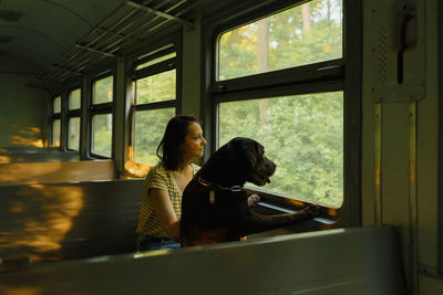 Woman and retriever dog ride a train, look out the window. traveling with a pet on public transport