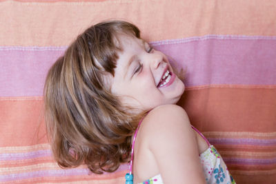 Smiling girl with eyes closed sitting on sofa